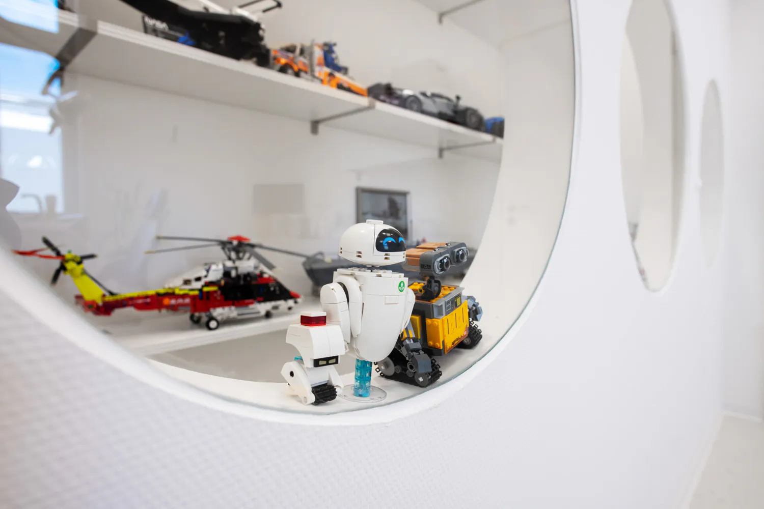 Lego-Modelle in unserer Praxis: WALL-E und EVE, ein Technik-Hubschrauber und Sportwagen auf den Regalen